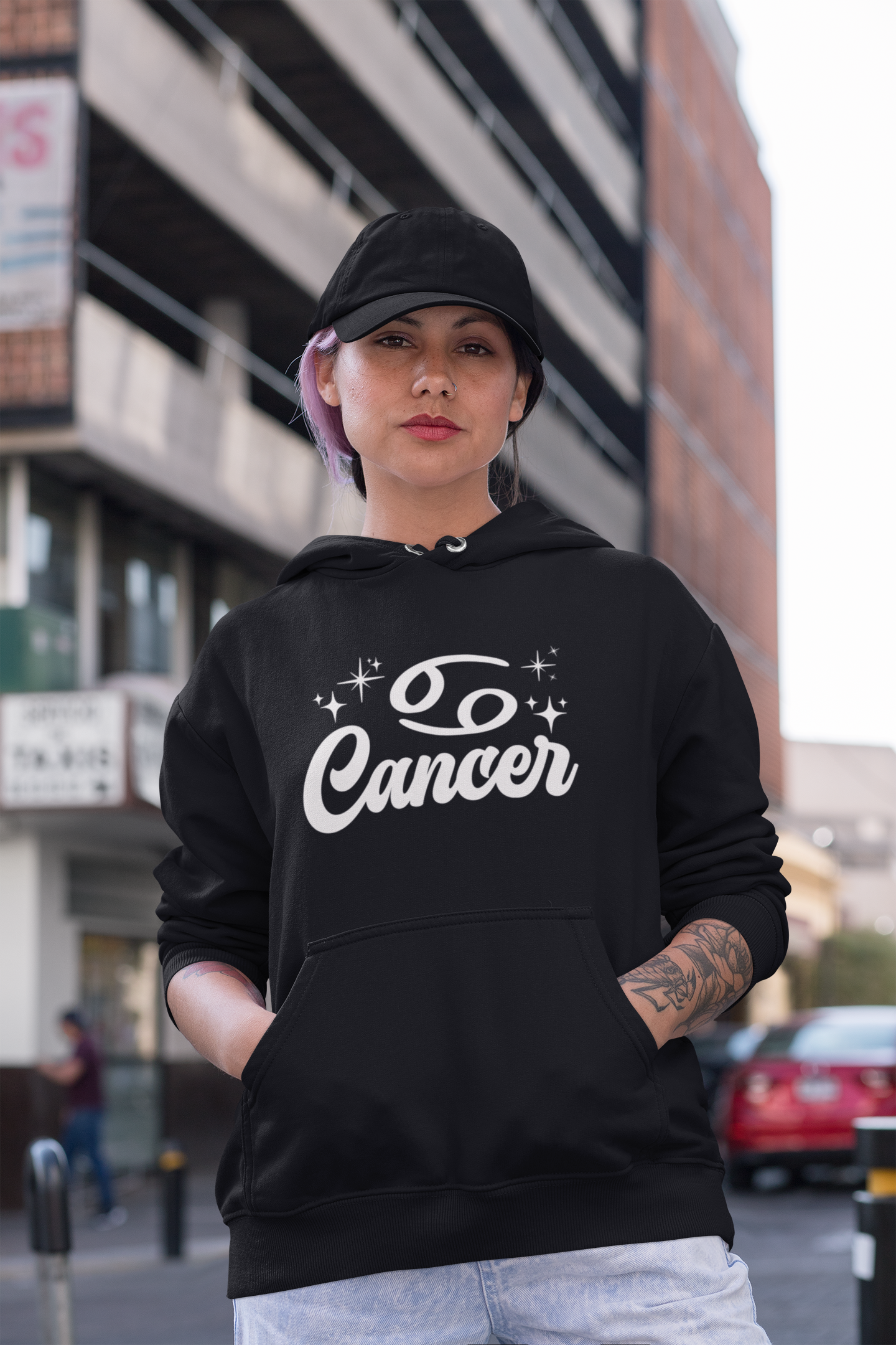 Person wearing a black hoodie with 'Cancer' white text in an urban setting