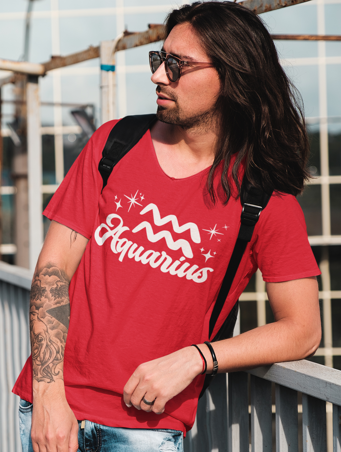 Person wearing a red 'Aquarius' t-shirt - white text design, with sunglasses and a backpack.
