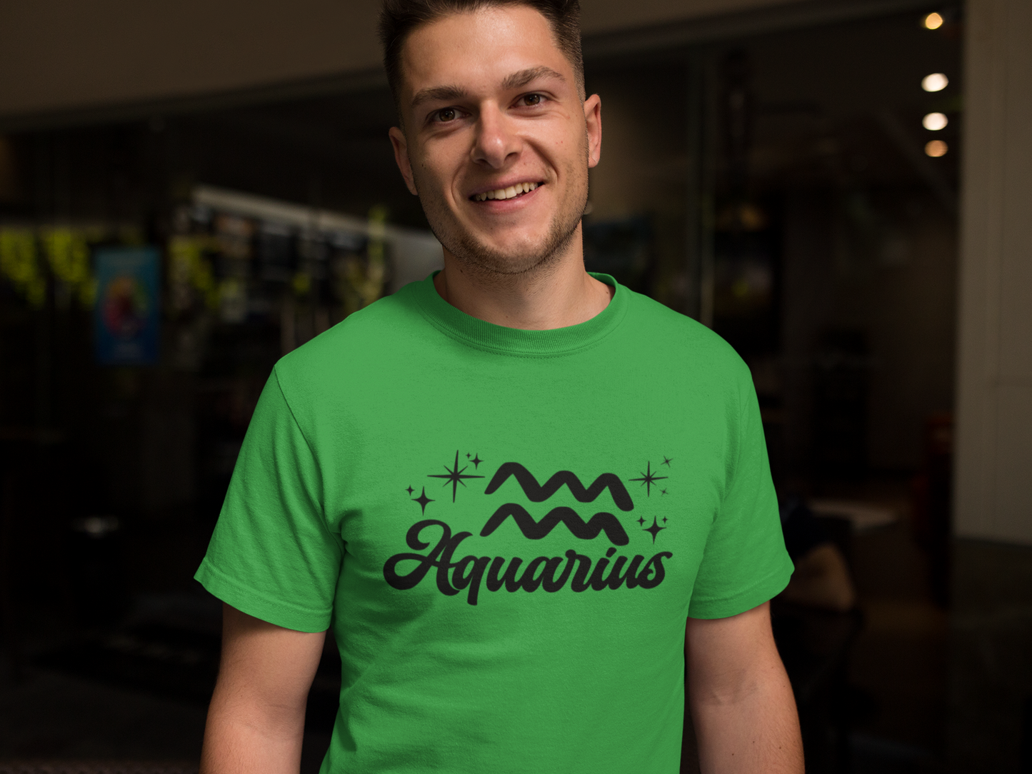 Person wearing a green t-shirt with 'Aquarius' black text design in a dark indoor setting