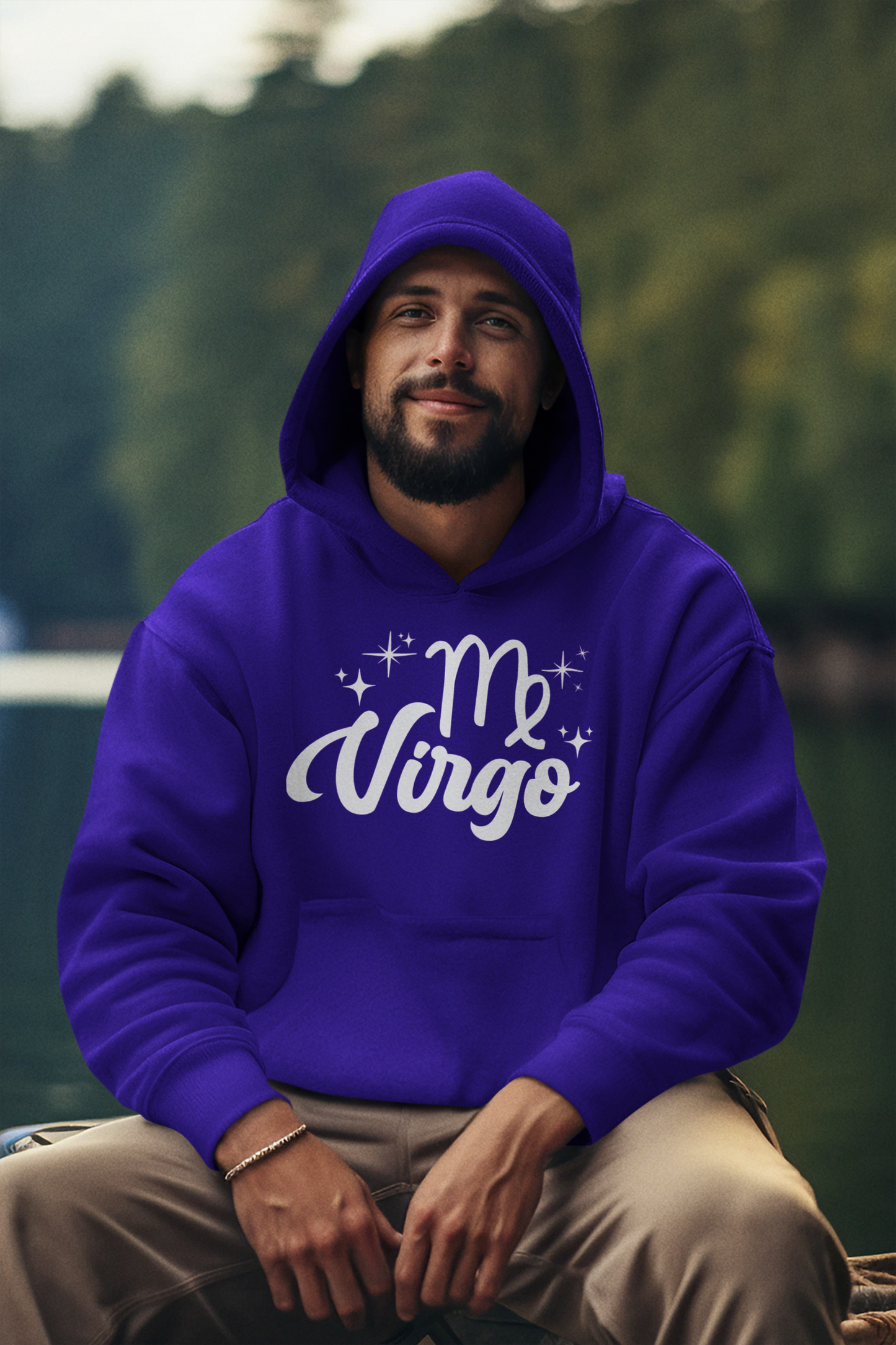 Man wearing a purple hoodie with 'Virgo' white text design, sitting outdoors with a blurred natural background