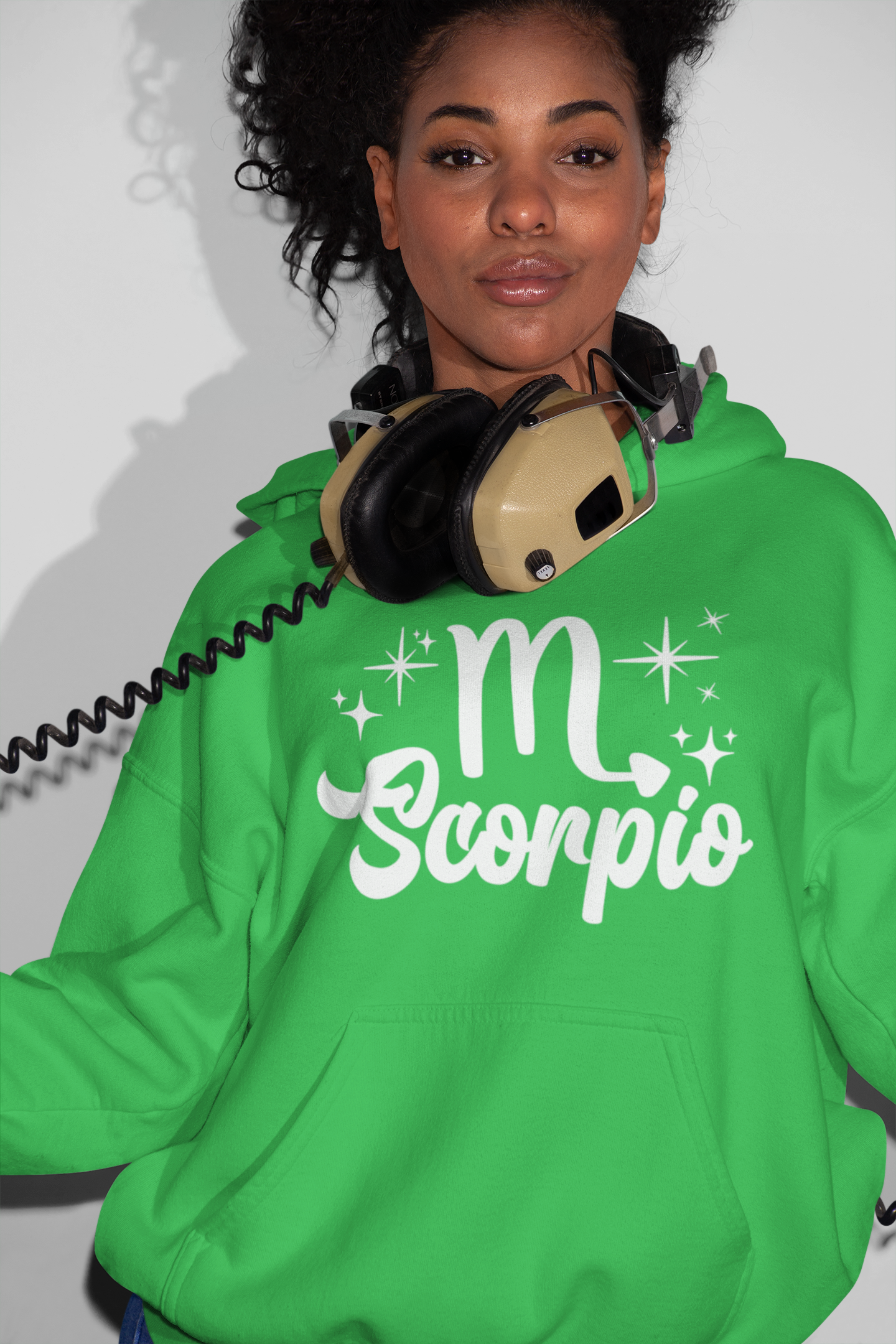 Person wearing a green hoodie with 'Scorpio' white text design, with headphones 