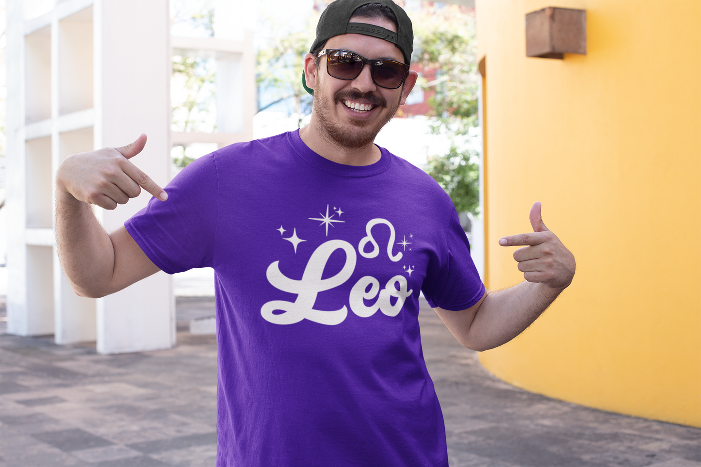 Man wearing a purple t-shirt with 'Leo' white text design, giving thumbs up outdoors.
