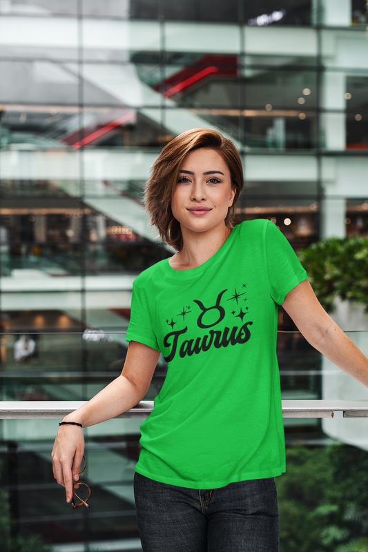 Person wearing a green Taurus t-shirt, black text design in front of a modern building.