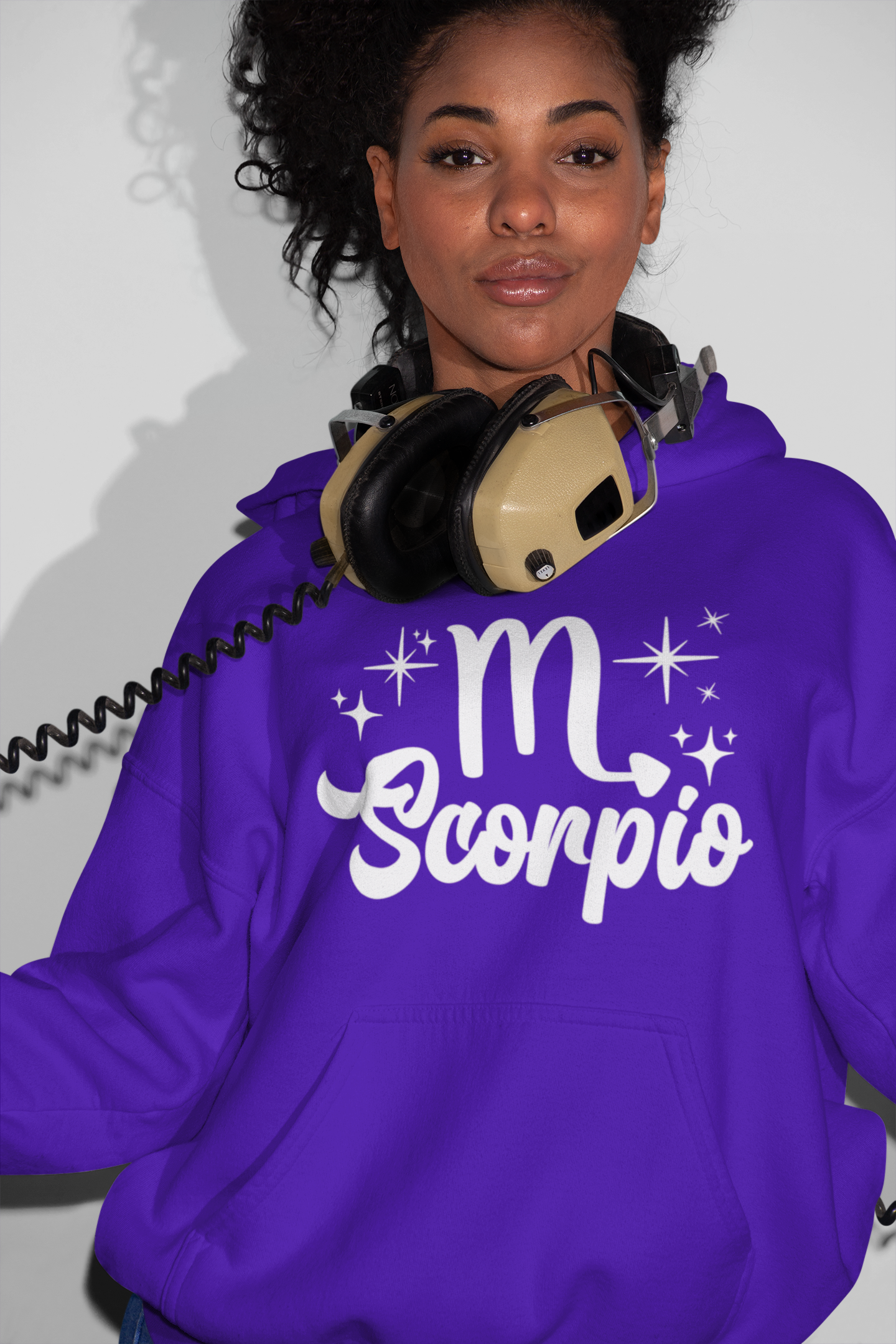 Person wearing a purple hoodie with 'Scorpio' white text design, with headphones 