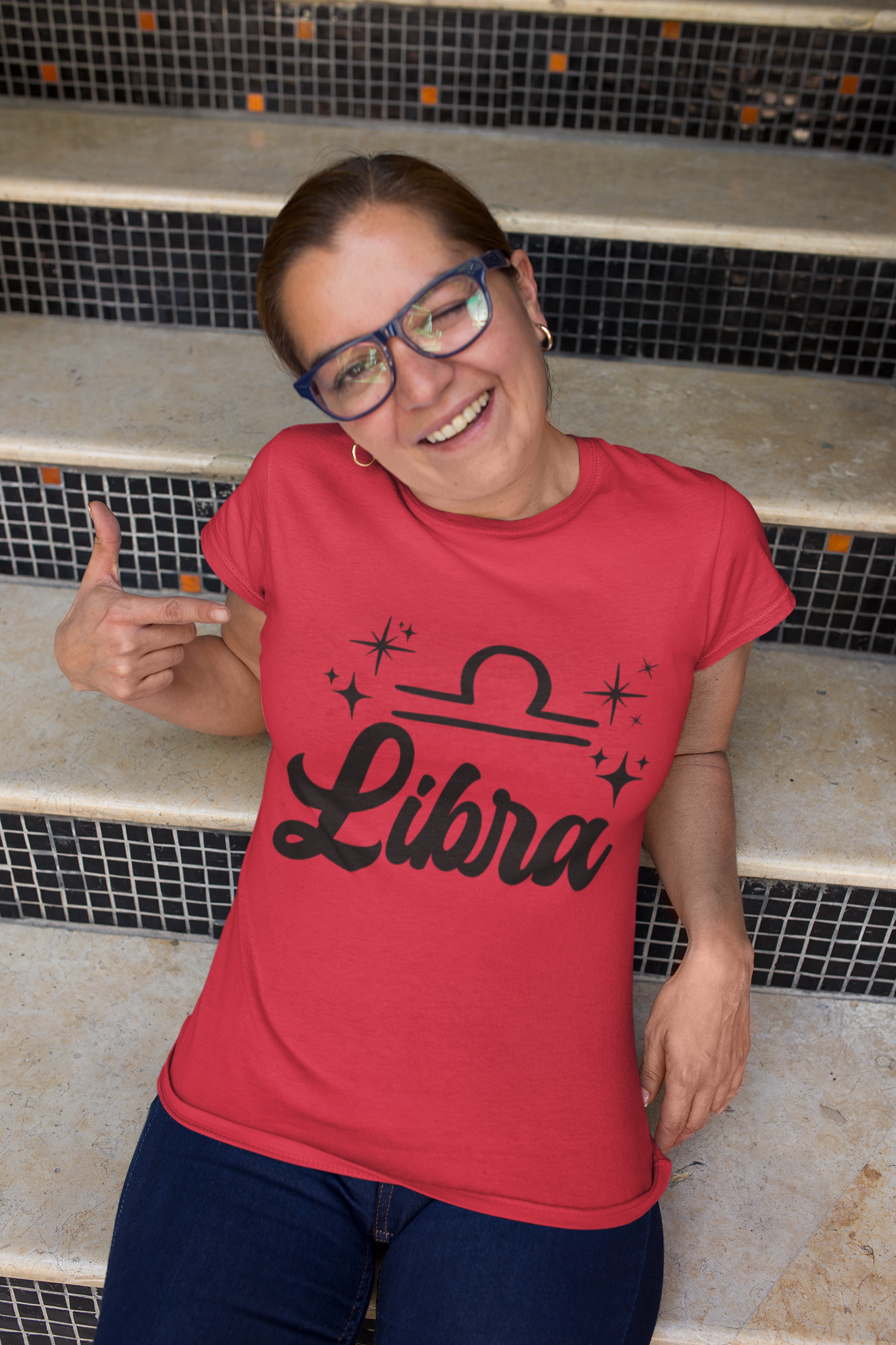 Person wearing a red 'Libra' black text design t-shirt sitting on steps.