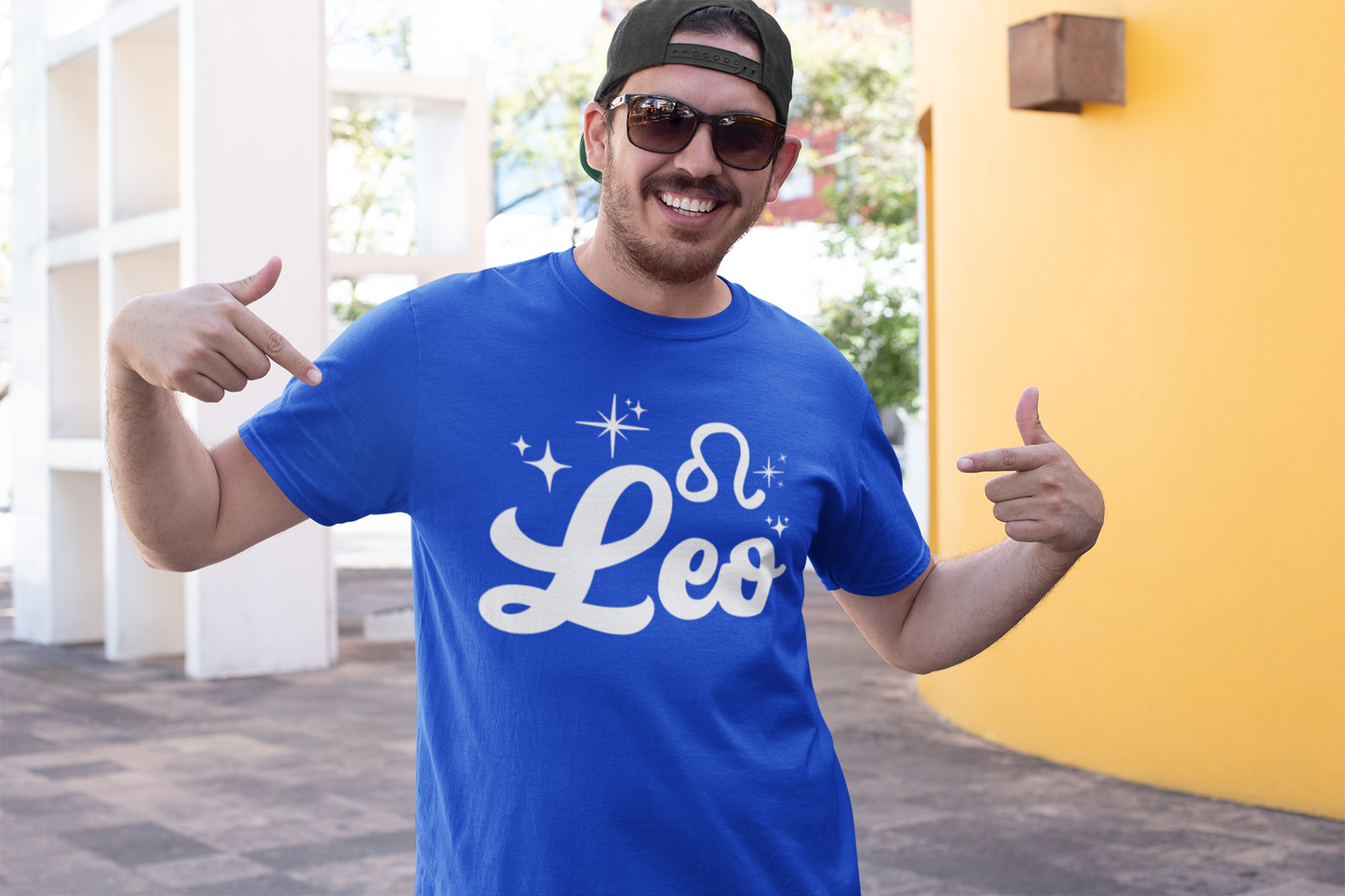 Man wearing a blue t-shirt with 'Leo' white text design, giving thumbs up outdoors.
