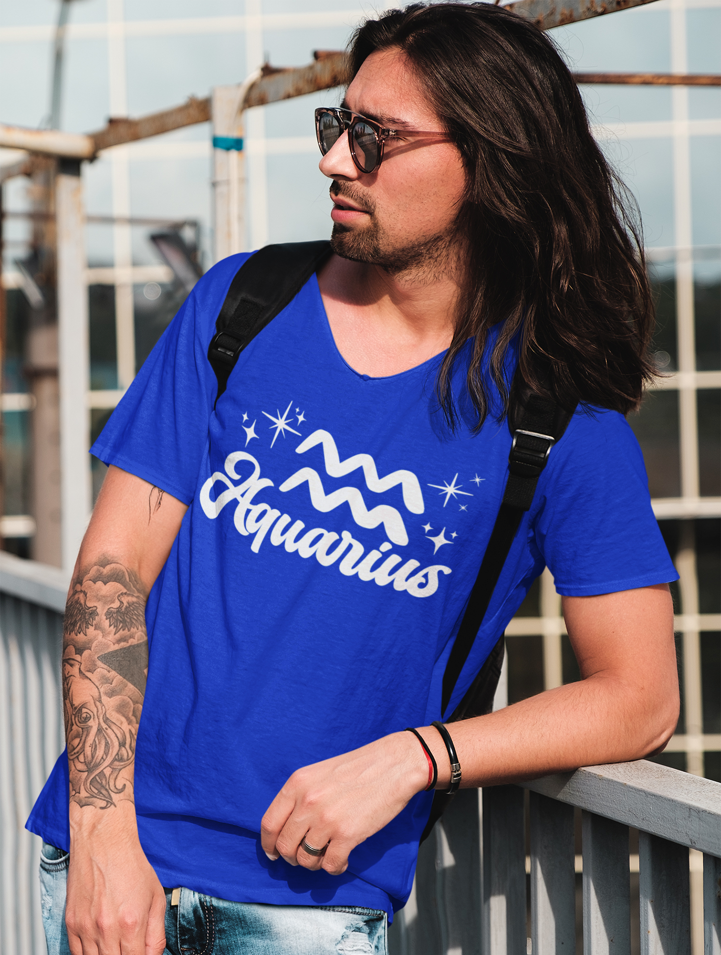 Person wearing a blue 'Aquarius' t-shirt - white text design, with sunglasses and a backpack.