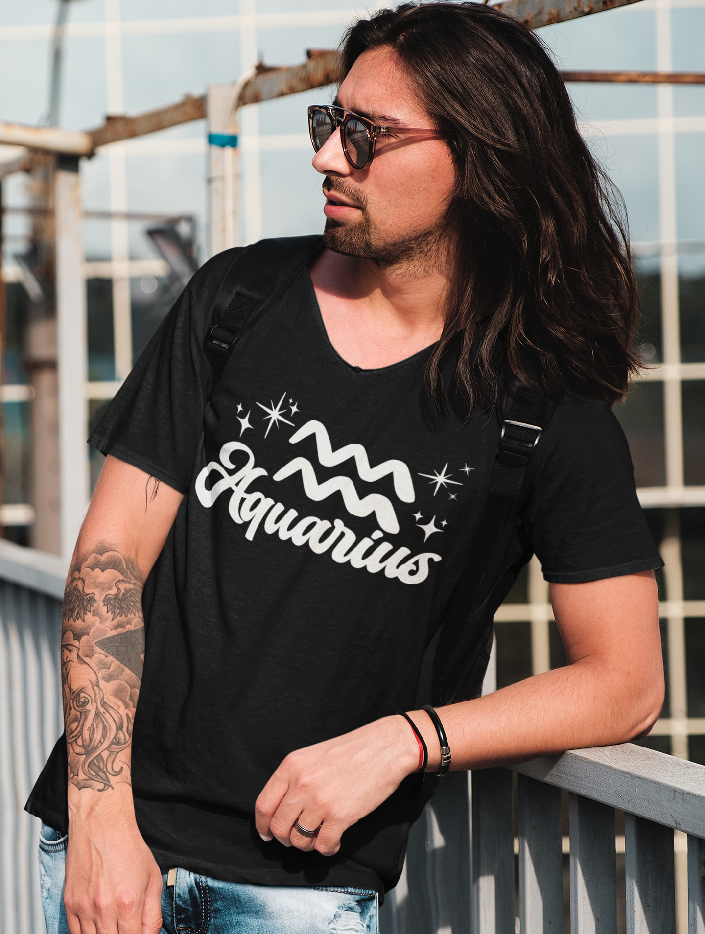 Person wearing a black 'Aquarius' t-shirt - white text design, with sunglasses and a backpack.