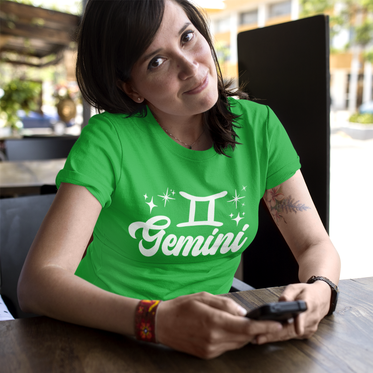 Person wearing a green t-shirt with 'Gemini' white text design sitting at a table.