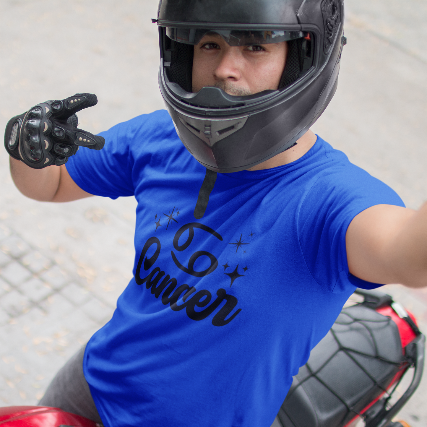 Person wearing a blue t-shirt with 'Leo Cancer' black text, black helmet, and gloves on a motorcycle.