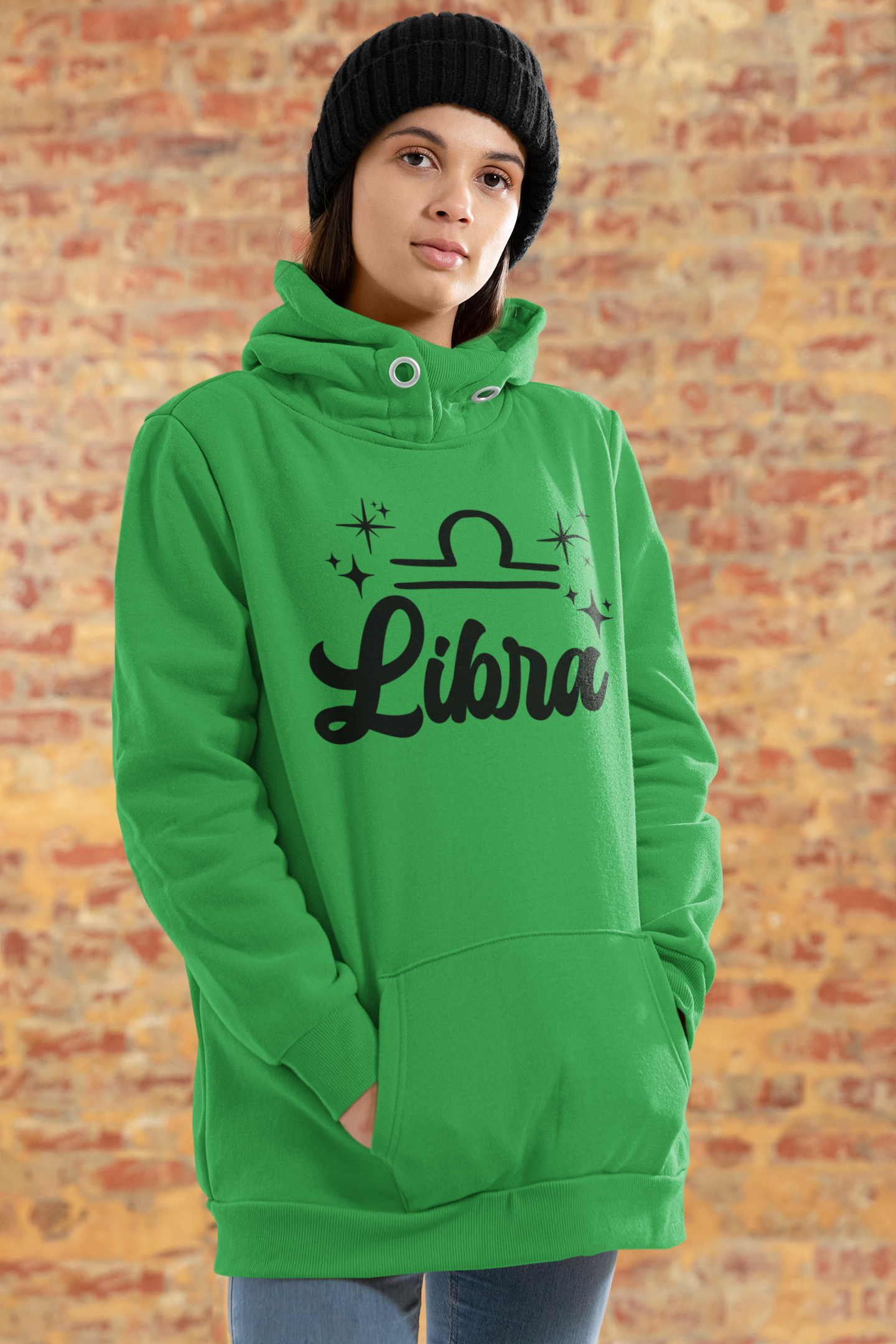 Person wearing a green hoodie with 'Libra' black text design standing in front of a brick wall.