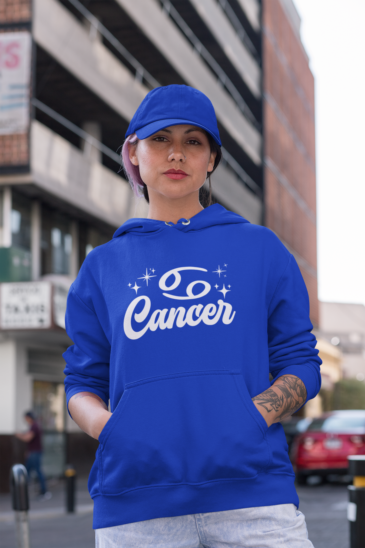 Person wearing a blue hoodie with 'Cancer' white text in an urban setting