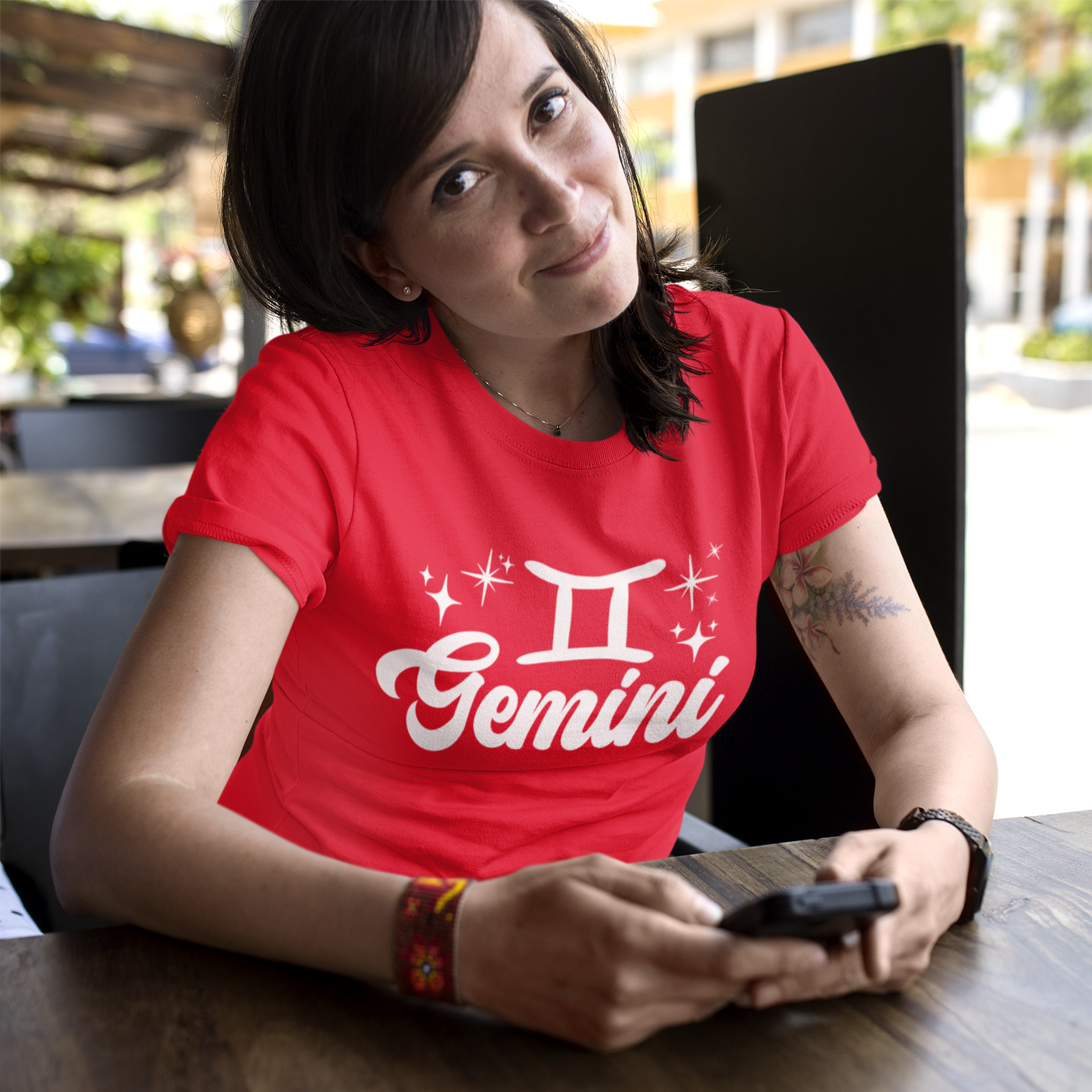 Person wearing a red t-shirt with 'Gemini' white text design sitting at a table.