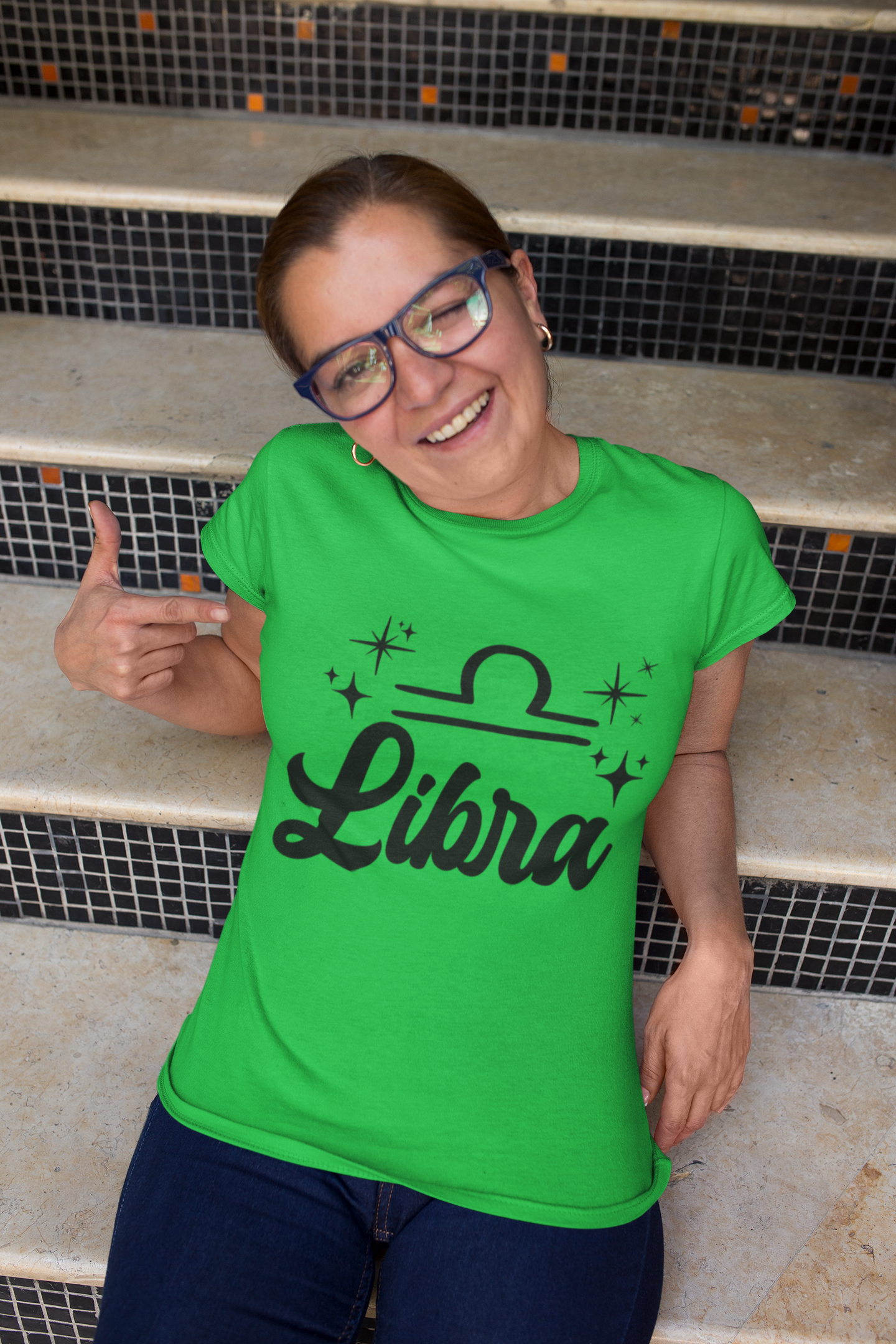 Person wearing a green 'Libra' black text design t-shirt sitting on steps.