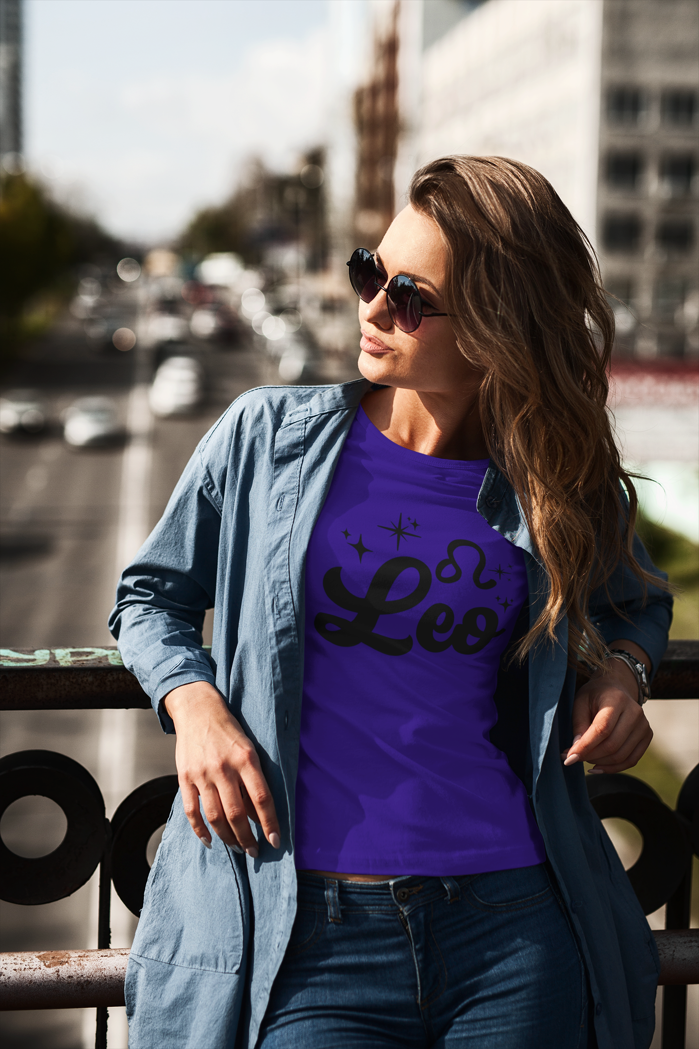 Woman wearing a purple t-shirt with 'Leo' black text design standing on a overpass.