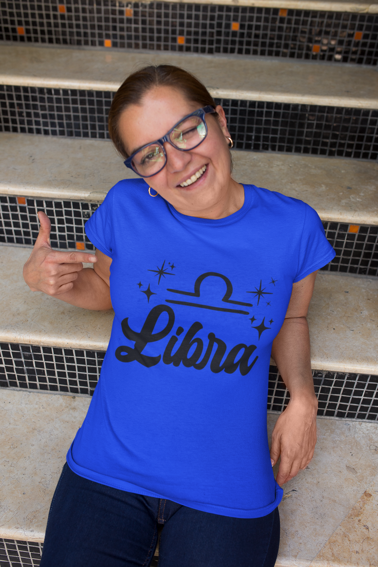 Person wearing a blue 'Libra' black text design t-shirt sitting on steps.