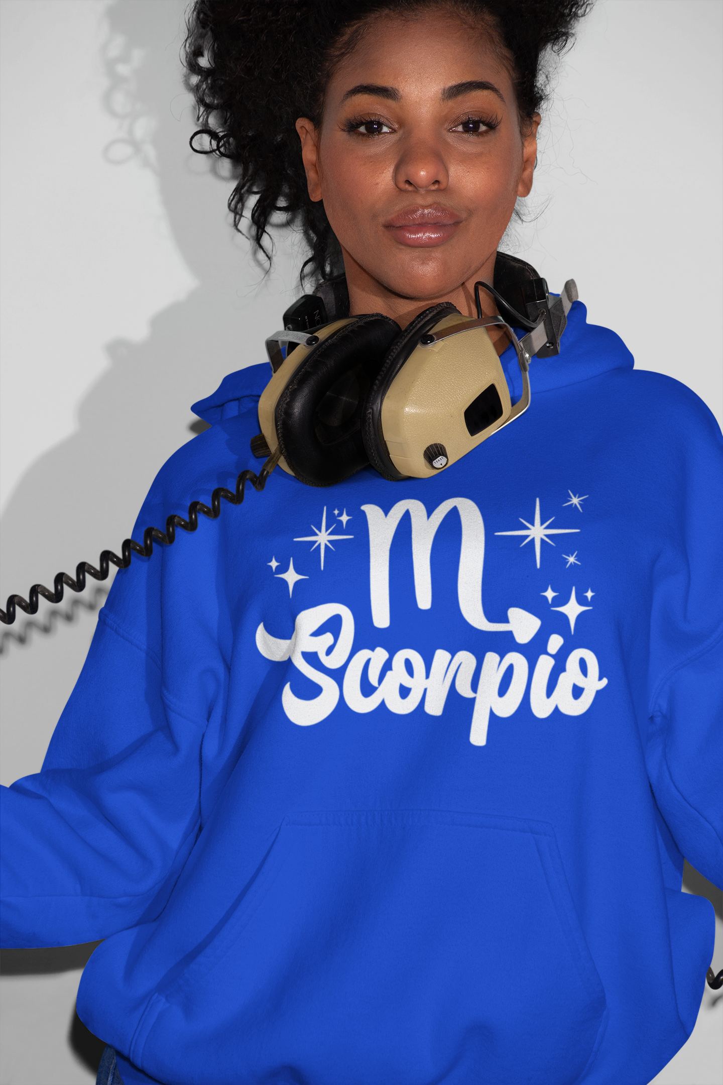 Person wearing a blue hoodie with 'Scorpio' white text design, with headphones 