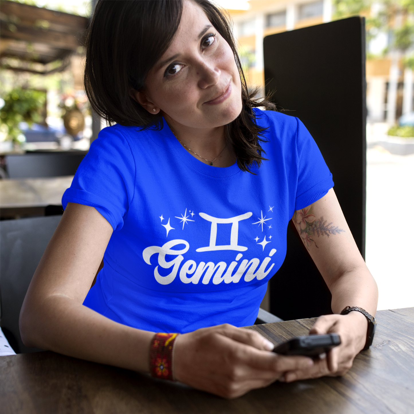 Person wearing a blue t-shirt with 'Gemini' white text design sitting at a table.