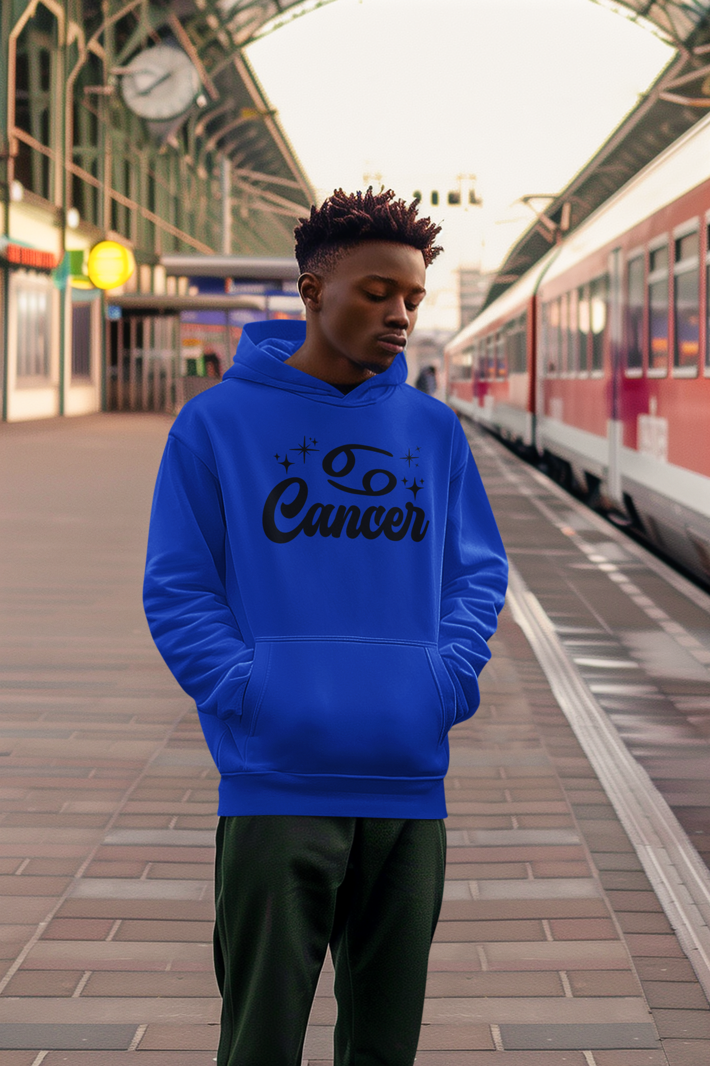 Person wearing an blue hoodie with 'Leo Cancer' black text at a train station.