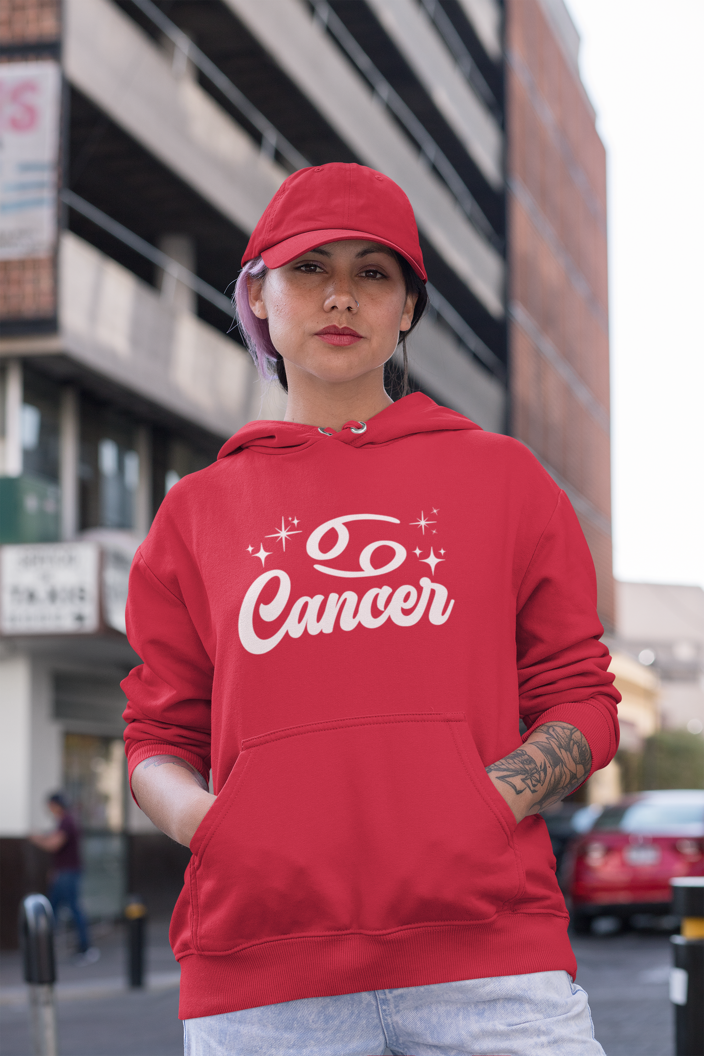 Person wearing a red hoodie with 'Cancer' white text in an urban setting